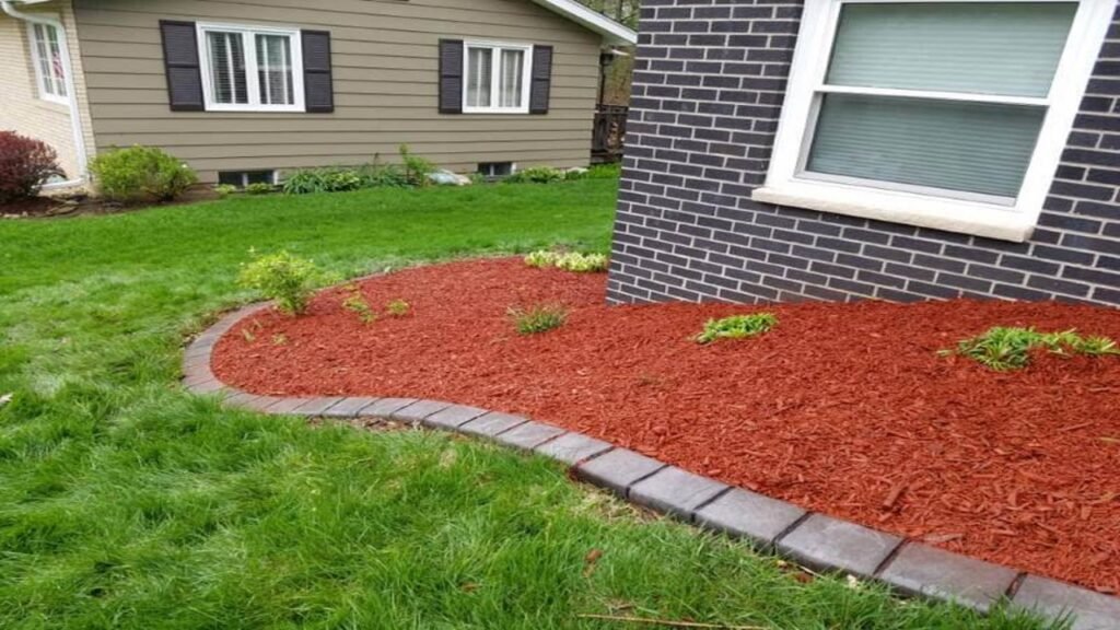 Fresh red mulch installed in a clean, well-maintained front yard garden bed