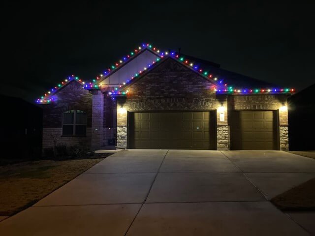 Professionally installed multi-colored Christmas lights cleanly outlining the roofline and peaks of a single-story home in Northern Colorado.