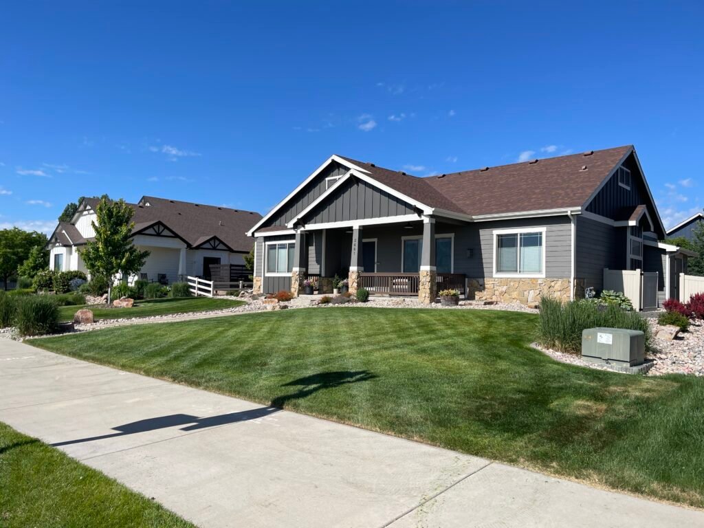 Wide view of a residential front yard showcasing freshly mown lawn stripes and clean, well-maintained landscaping in a Johnstown, Colorado neighborhood.