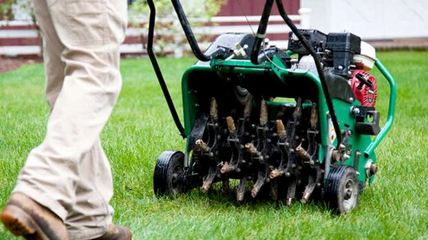 Professional commercial core aeration machine actively loosening dense lawn soil in Northern Colorado.